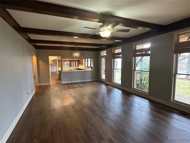 unfurnished living room featuring ceiling fan with notable chandelier, beam ceiling, dark hardwood / wood-style flooring, and a textured ceiling