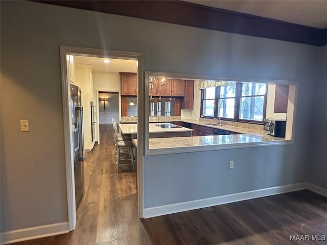 kitchen with black electric stovetop, a kitchen breakfast bar, sink, dark hardwood / wood-style floors, and kitchen peninsula