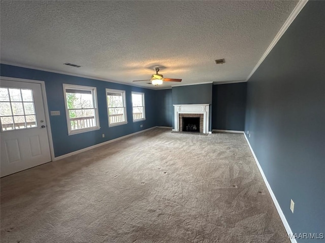 unfurnished living room with carpet flooring, ceiling fan, a brick fireplace, crown molding, and a textured ceiling