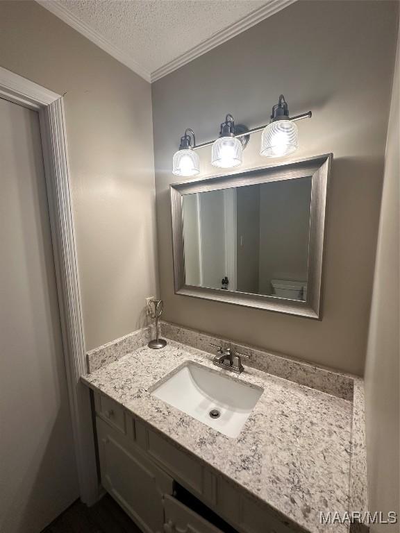 bathroom with vanity, toilet, crown molding, and a textured ceiling