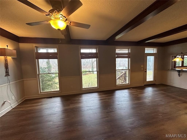 empty room with beamed ceiling, a textured ceiling, dark hardwood / wood-style flooring, and ceiling fan