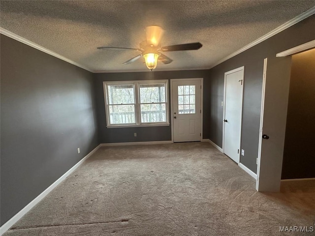 carpeted spare room with a textured ceiling, ceiling fan, and ornamental molding