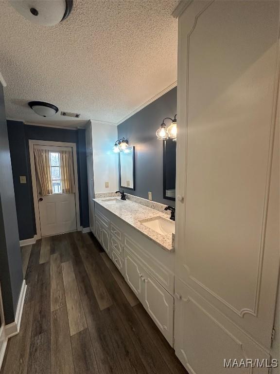 bathroom featuring crown molding, vanity, a textured ceiling, and hardwood / wood-style flooring