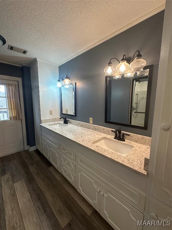 bathroom featuring hardwood / wood-style floors, vanity, ornamental molding, and a textured ceiling