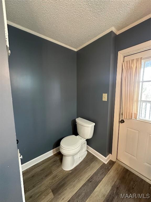 bathroom with crown molding, toilet, a textured ceiling, and hardwood / wood-style flooring