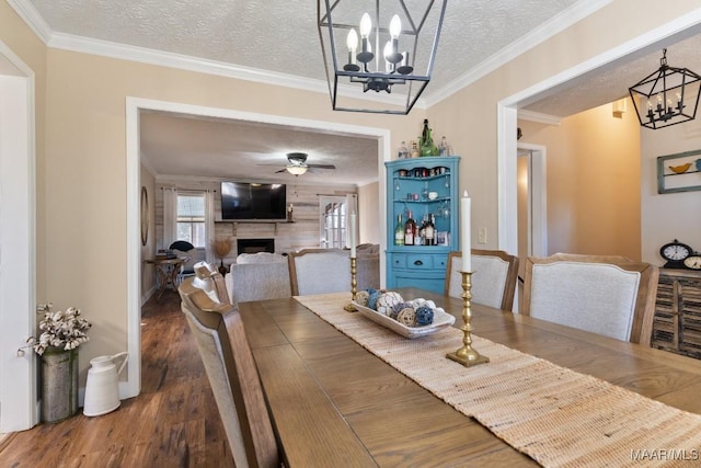 dining area with wood-type flooring, ceiling fan with notable chandelier, crown molding, and a textured ceiling