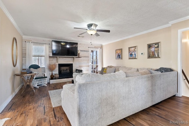 living room with ceiling fan, dark hardwood / wood-style floors, a fireplace, a textured ceiling, and ornamental molding