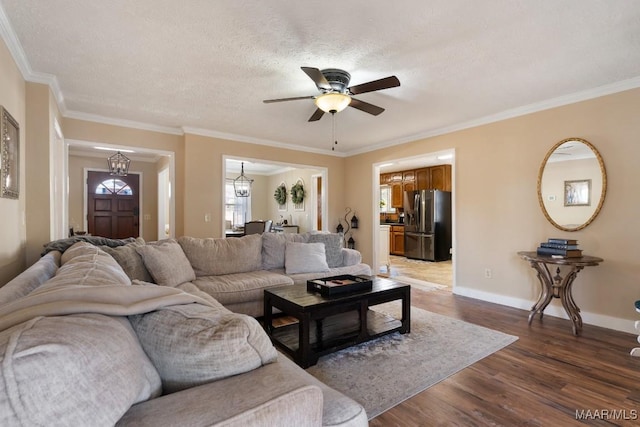 living room featuring ceiling fan with notable chandelier, dark wood-type flooring, a textured ceiling, and ornamental molding