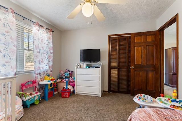 bedroom with ceiling fan, carpet floors, and a textured ceiling