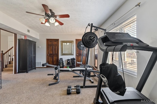 workout room with a textured ceiling, ceiling fan, and carpet floors