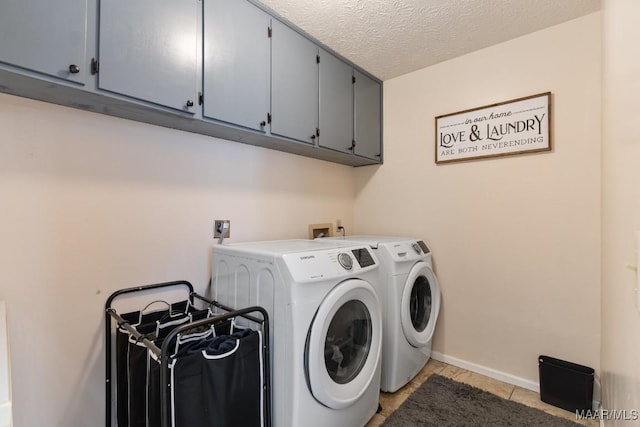 washroom featuring a textured ceiling, cabinets, washer and dryer, and light tile patterned floors