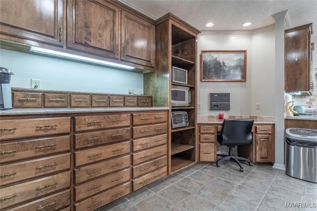 office space featuring a textured ceiling, built in desk, and crown molding