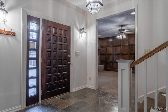 carpeted foyer entrance featuring a textured ceiling, ceiling fan, and ornamental molding