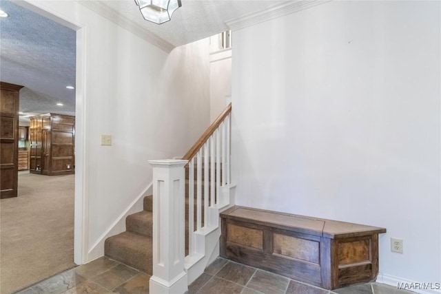 stairway featuring carpet, ornamental molding, and a textured ceiling