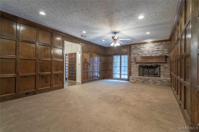 unfurnished living room featuring carpet flooring, a fireplace, a textured ceiling, and wooden walls