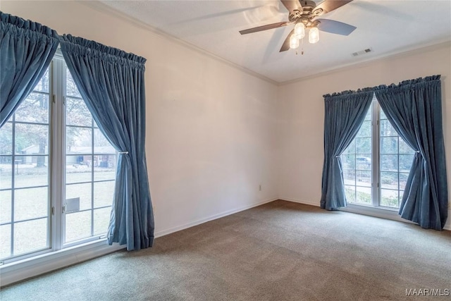 carpeted empty room featuring ceiling fan, a healthy amount of sunlight, and ornamental molding