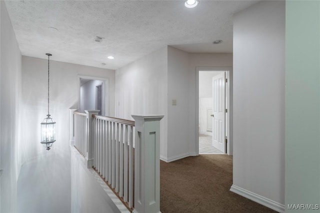 corridor featuring a textured ceiling and carpet floors