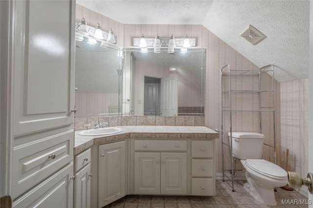 bathroom featuring vanity, toilet, lofted ceiling, and a textured ceiling