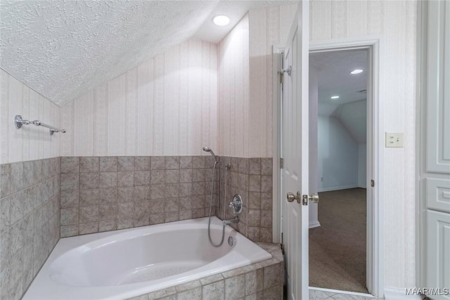 bathroom featuring a relaxing tiled tub, a textured ceiling, and vaulted ceiling