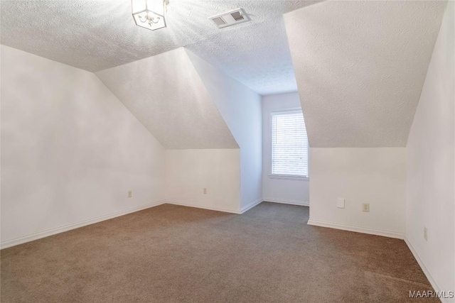 additional living space featuring lofted ceiling, carpet floors, and a textured ceiling