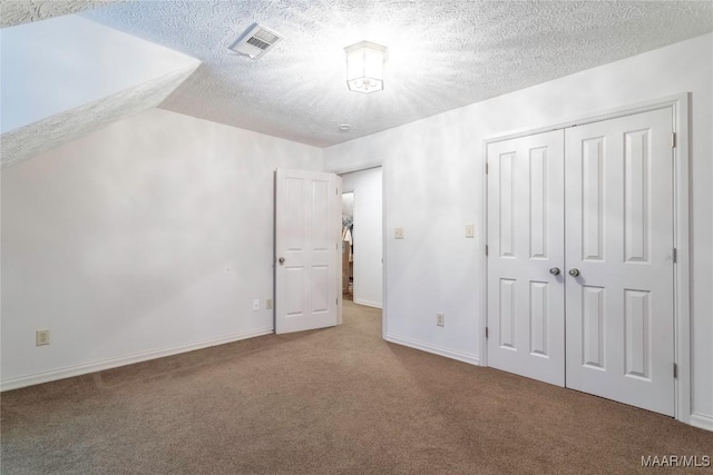 unfurnished bedroom with a closet, carpet floors, and a textured ceiling