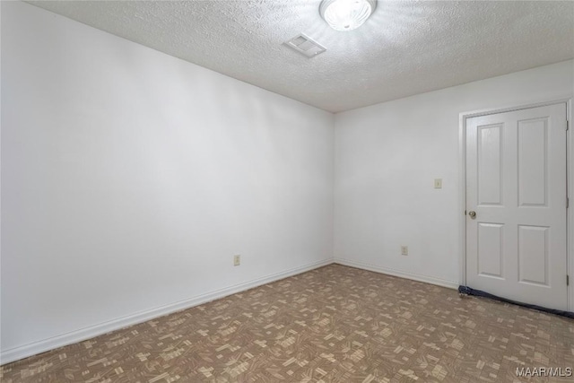 empty room featuring light parquet floors and a textured ceiling