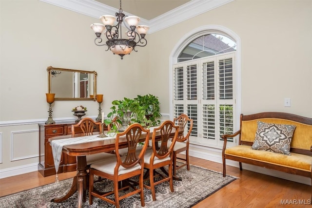 dining room with ornamental molding, hardwood / wood-style flooring, and a notable chandelier