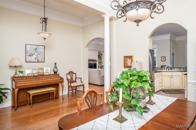 dining space featuring crown molding, sink, and light hardwood / wood-style floors