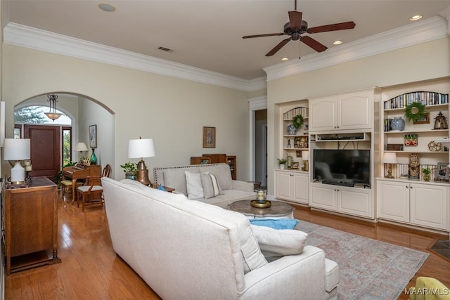 living room featuring ceiling fan, crown molding, and light wood-type flooring