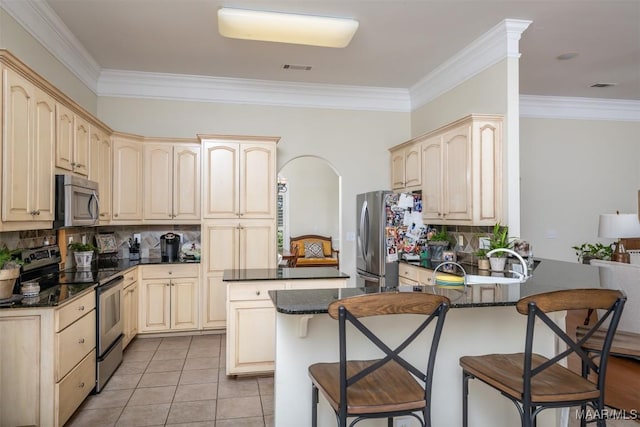 kitchen featuring light tile patterned floors, ornamental molding, a kitchen bar, kitchen peninsula, and stainless steel appliances