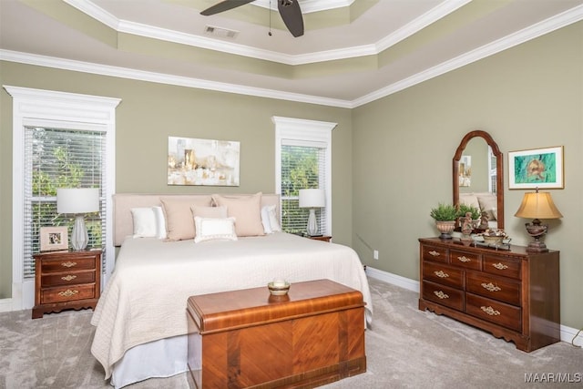 carpeted bedroom with a raised ceiling, multiple windows, ceiling fan, and crown molding