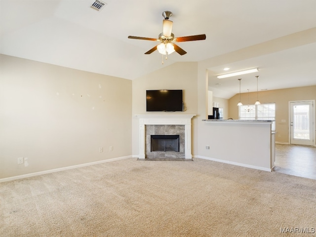 unfurnished living room featuring a tile fireplace, light colored carpet, vaulted ceiling, and ceiling fan