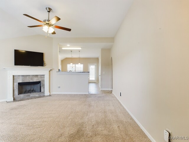 unfurnished living room with light carpet, vaulted ceiling, ceiling fan, and a tiled fireplace