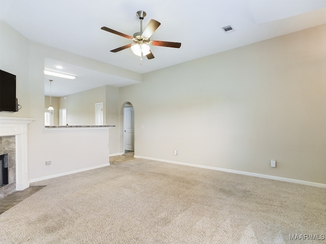 unfurnished living room featuring a fireplace, light colored carpet, and ceiling fan