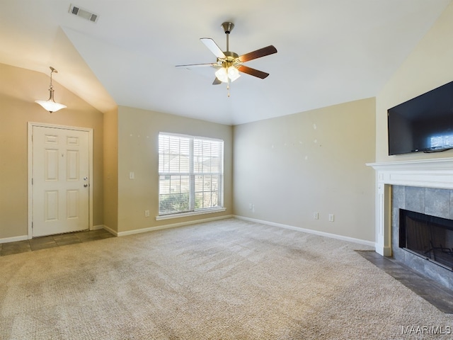 unfurnished living room with a tile fireplace, ceiling fan, carpet floors, and vaulted ceiling