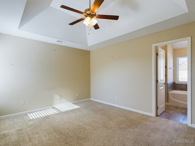 carpeted empty room with a raised ceiling and ceiling fan