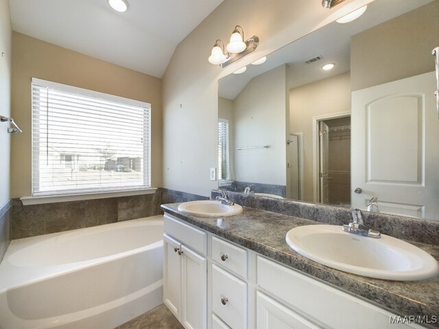 bathroom with vanity, vaulted ceiling, and a tub