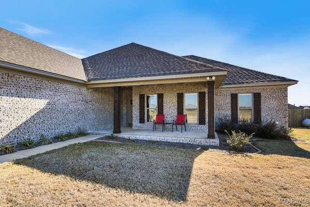 rear view of property featuring covered porch and a lawn