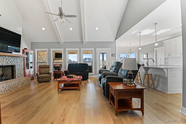 living room featuring ceiling fan, high vaulted ceiling, light wood-type flooring, and a brick fireplace