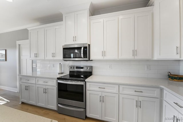 kitchen with white cabinets, decorative backsplash, light wood-type flooring, and stainless steel appliances