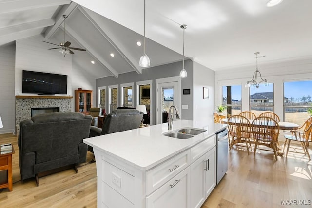 kitchen with hanging light fixtures, ceiling fan with notable chandelier, a kitchen island with sink, and sink