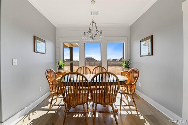 dining space with ornamental molding, a chandelier, and wood-type flooring