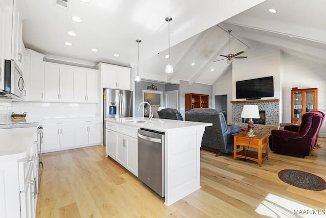 kitchen with tasteful backsplash, a kitchen island with sink, white cabinetry, and appliances with stainless steel finishes