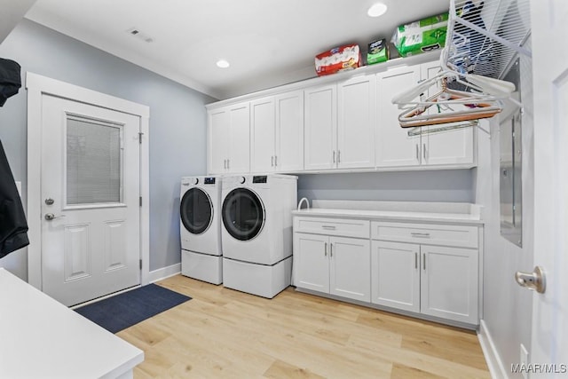 laundry area with cabinets, light hardwood / wood-style floors, and washing machine and clothes dryer