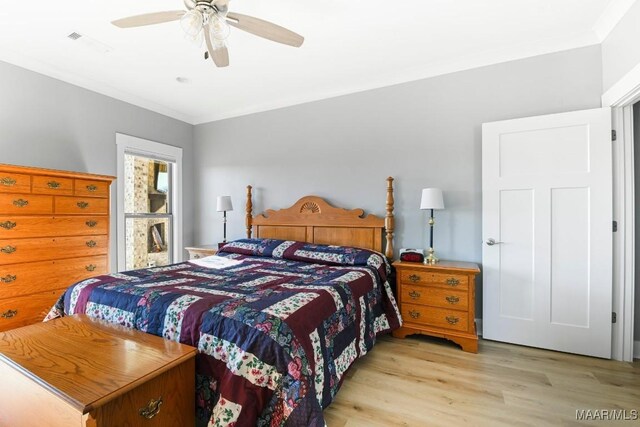 bedroom with light wood-type flooring, ceiling fan, and crown molding