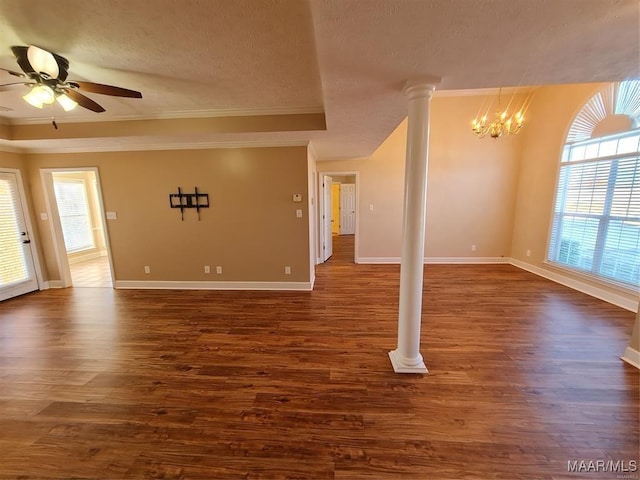 empty room with ceiling fan with notable chandelier, dark hardwood / wood-style floors, ornamental molding, a textured ceiling, and decorative columns