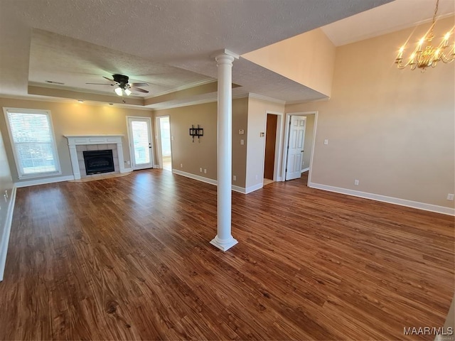 unfurnished living room with dark hardwood / wood-style flooring, ceiling fan with notable chandelier, a tray ceiling, a textured ceiling, and a tile fireplace