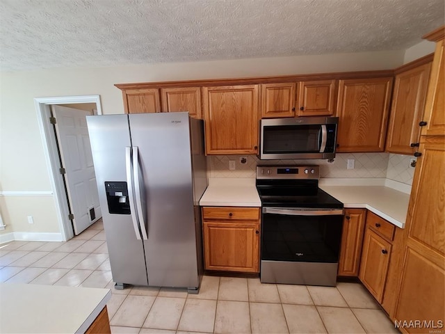 kitchen with decorative backsplash, light tile patterned flooring, a textured ceiling, and appliances with stainless steel finishes