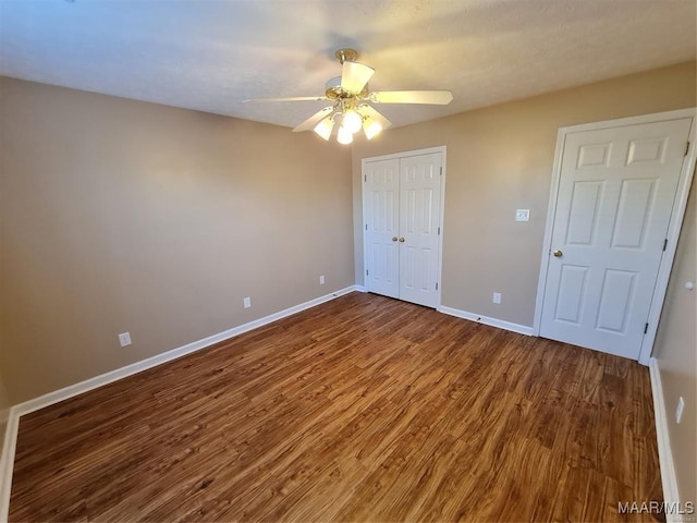 unfurnished bedroom with a closet, ceiling fan, and dark wood-type flooring