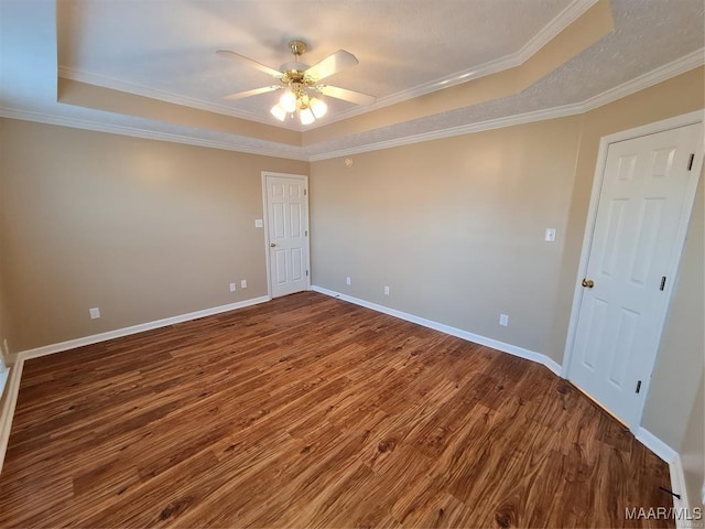 empty room featuring hardwood / wood-style floors, a tray ceiling, ceiling fan, and ornamental molding